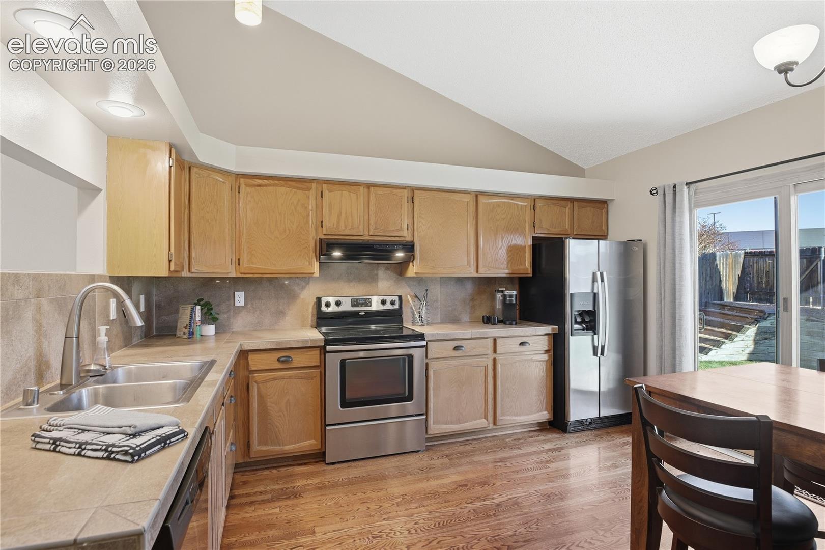 KITCHEN AND DINING AREA FEATURE TILE COUNTERTOPS, STAINLESS STEEL APPLIANCES, BUILT-IN SHELVING AND A WALKOUT TO THE SPACIOUS BACKYARD