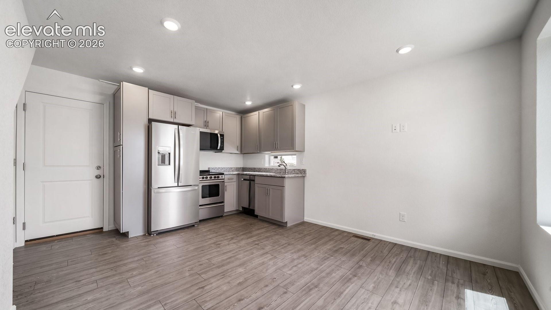 Kitchen featuring stainless steel appliances, wood-finish flooring, recessed lighting, shaker-style cabinetry, and a double-basin sink
*photos of a model home*
