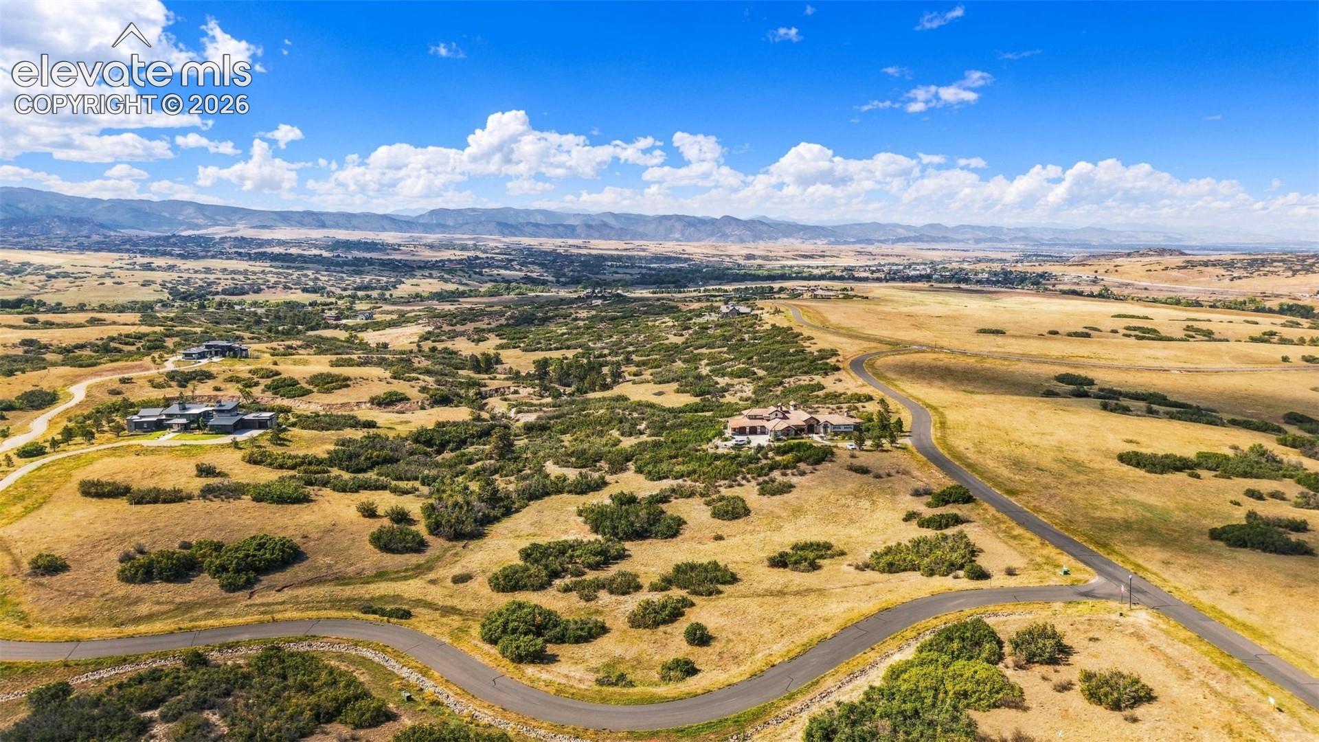 Expansive rural landscape featuring scattered brush and distant mountain ranges
