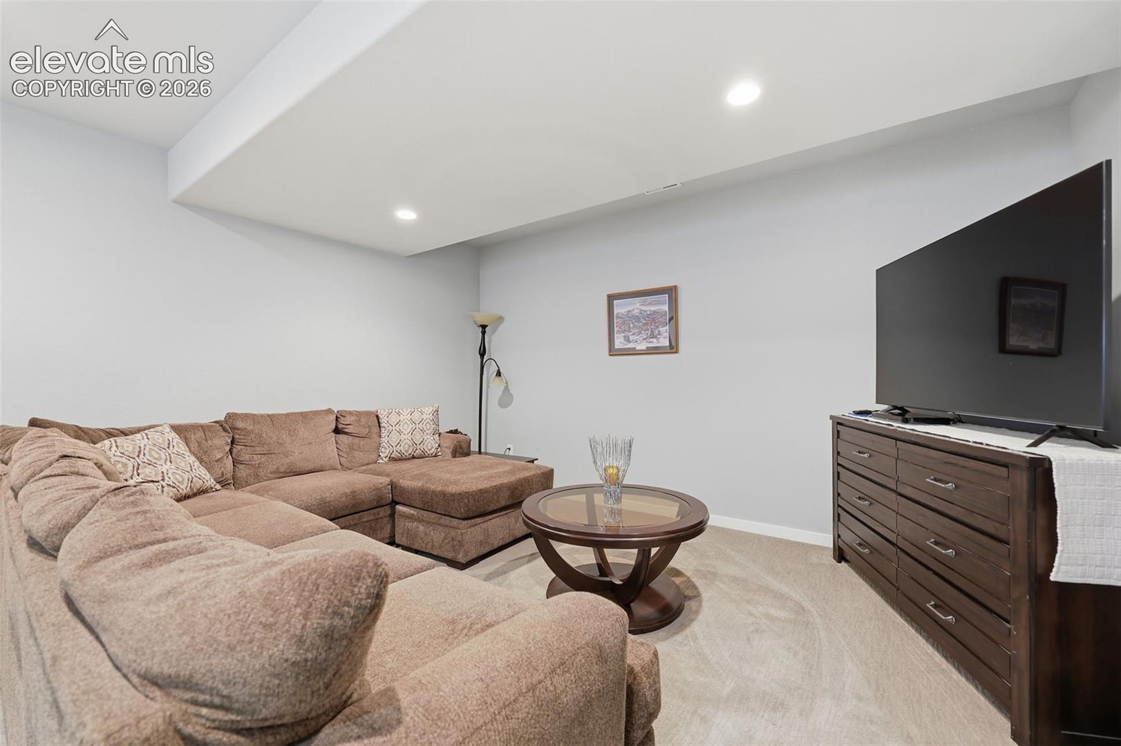 Recessed lighting illuminates the space, featuring light gray walls and light-colored carpeting.