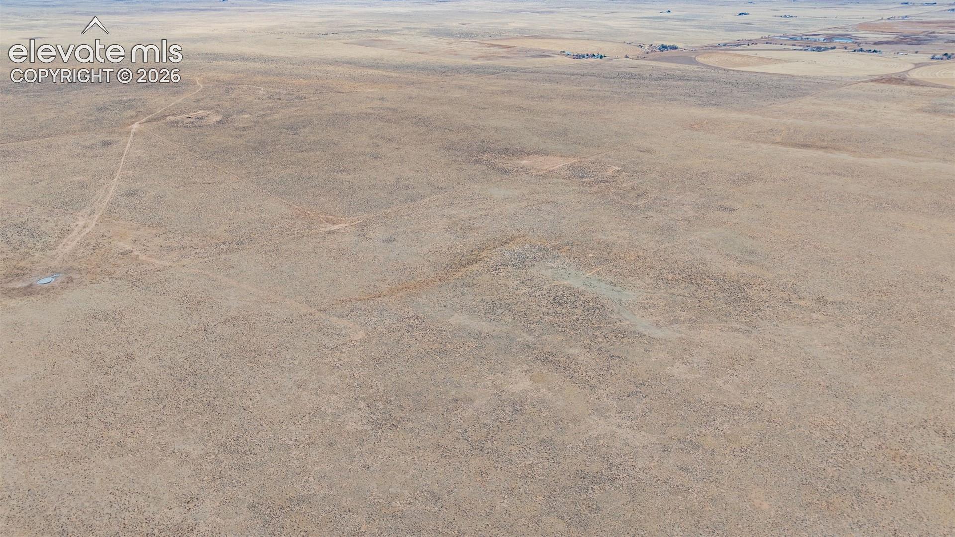 Expansive acreage featuring native high-desert vegetation, level topography, and an existing dirt access path