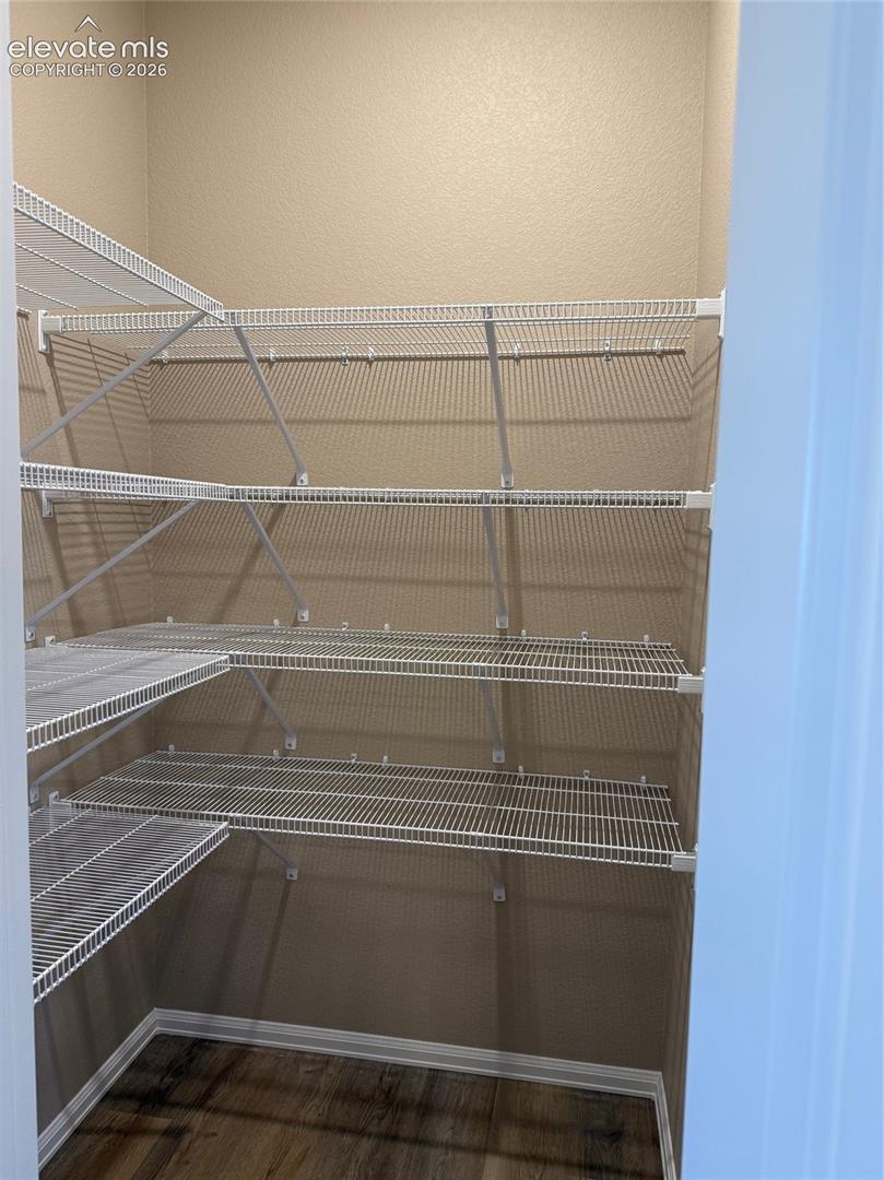 Expansive walk-in pantry with multiple levels of wire shelving and wood-finish flooring