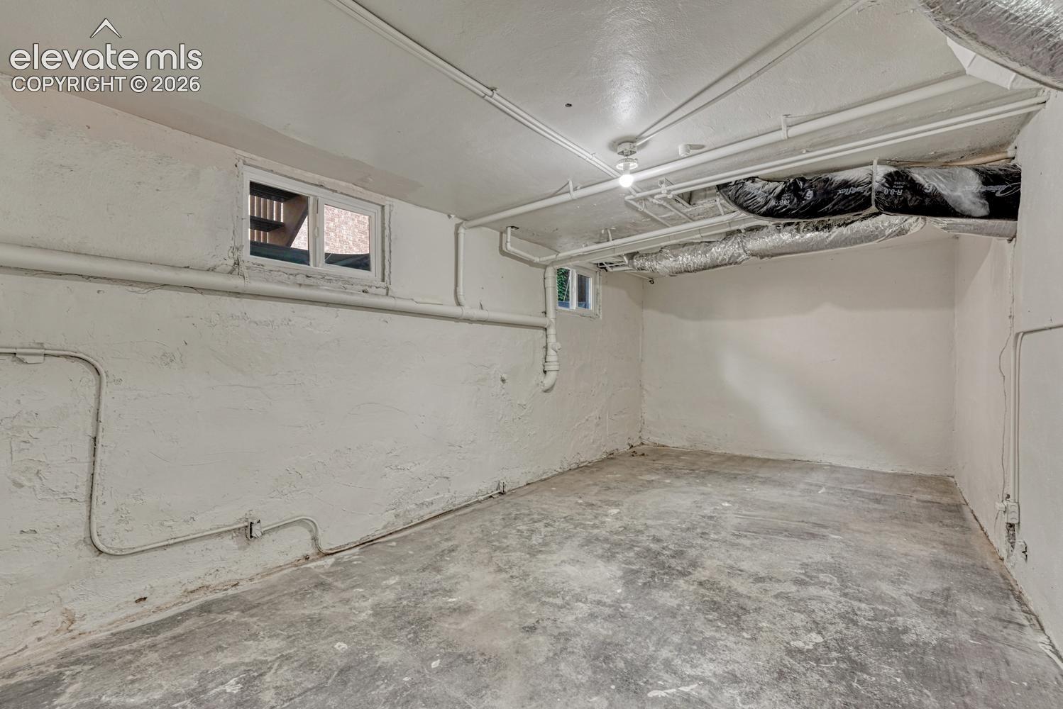 Unfinished basement space with exposed utilities and concrete flooring