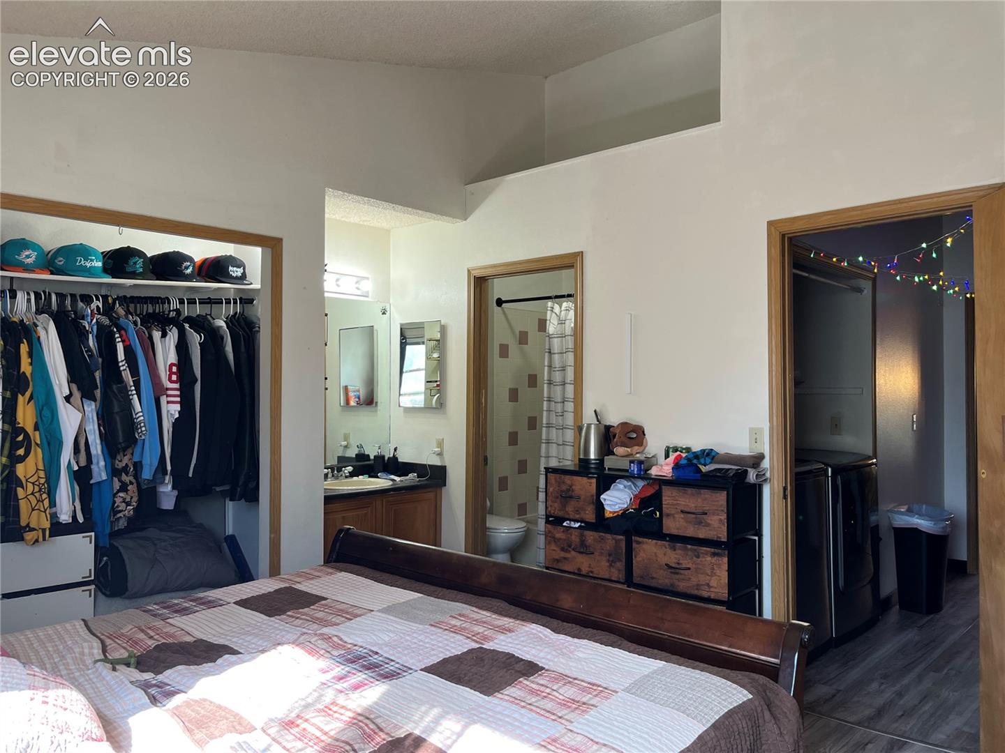 Vaulted ceiling with architectural ledge, built-in closet shelving, and vanity with stone-finish countertop