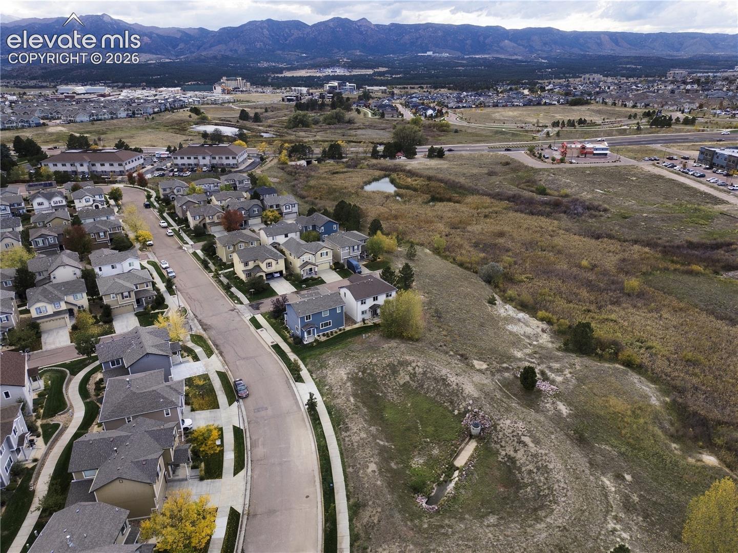 Aerial perspective featuring suburban residential streets, expansive open terrain, and prominent mountain range backdrop