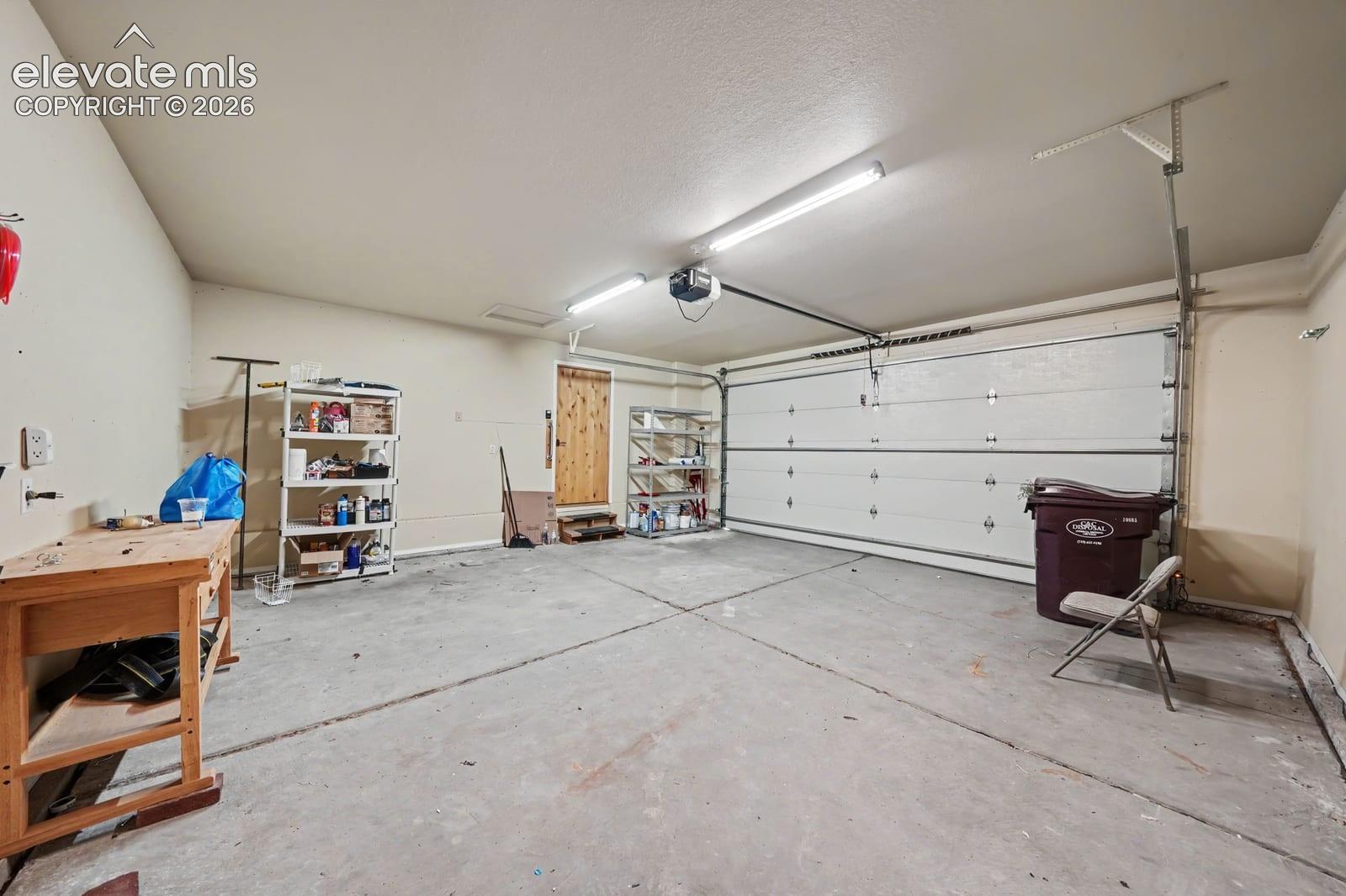 Two-car garage featuring a concrete floor, motorized sectional overhead door, and overhead LED lighting