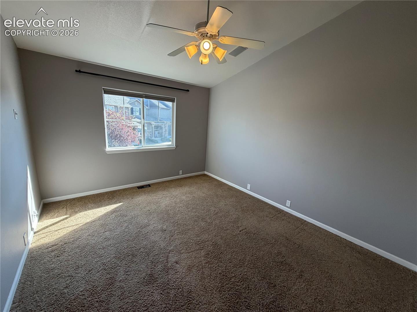 Neutral-toned walls, carpeted flooring, and a ceiling fan with integrated lighting