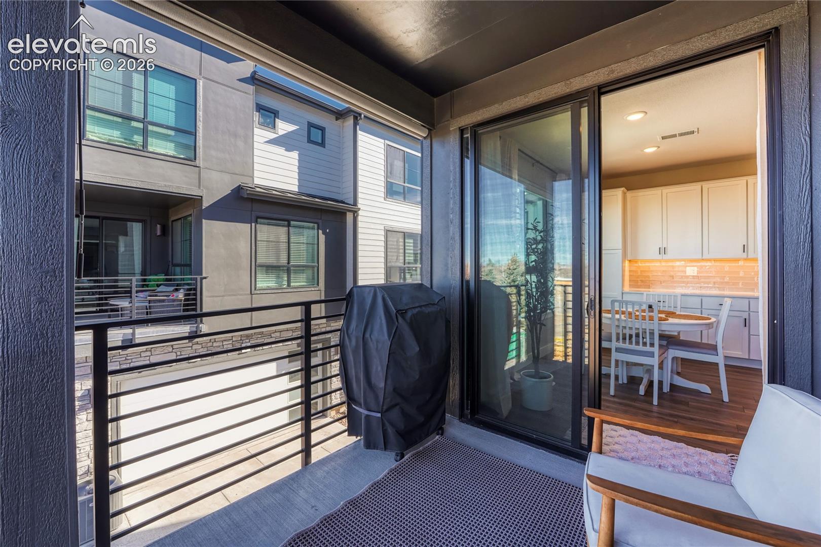 Covered balcony featuring concrete flooring, black metal railing, and floor-to-ceiling sliding glass doors