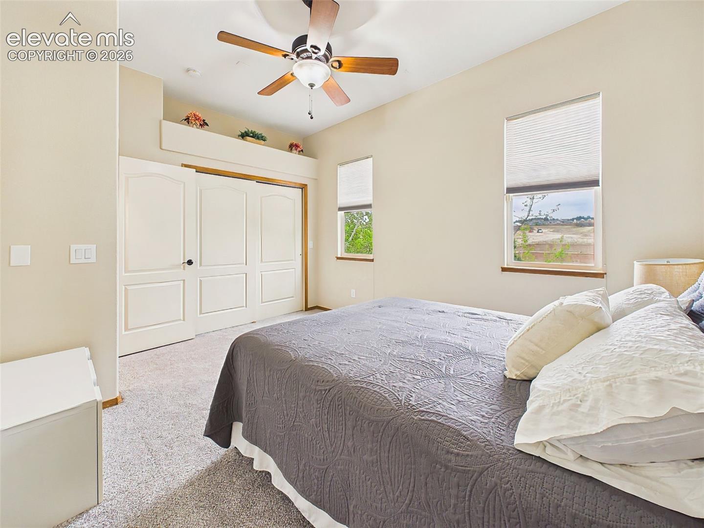Comfortable secondary bedroom with soft carpeting, ceiling fan, and ample closet space.