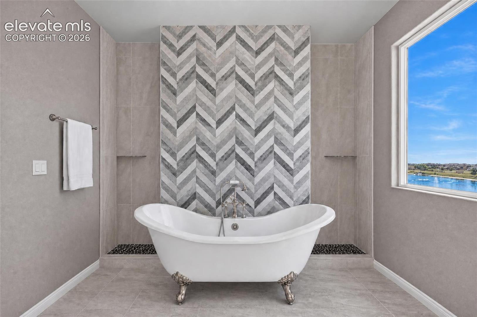 Freestanding clawfoot tub with a chevron-patterned tile accent wall