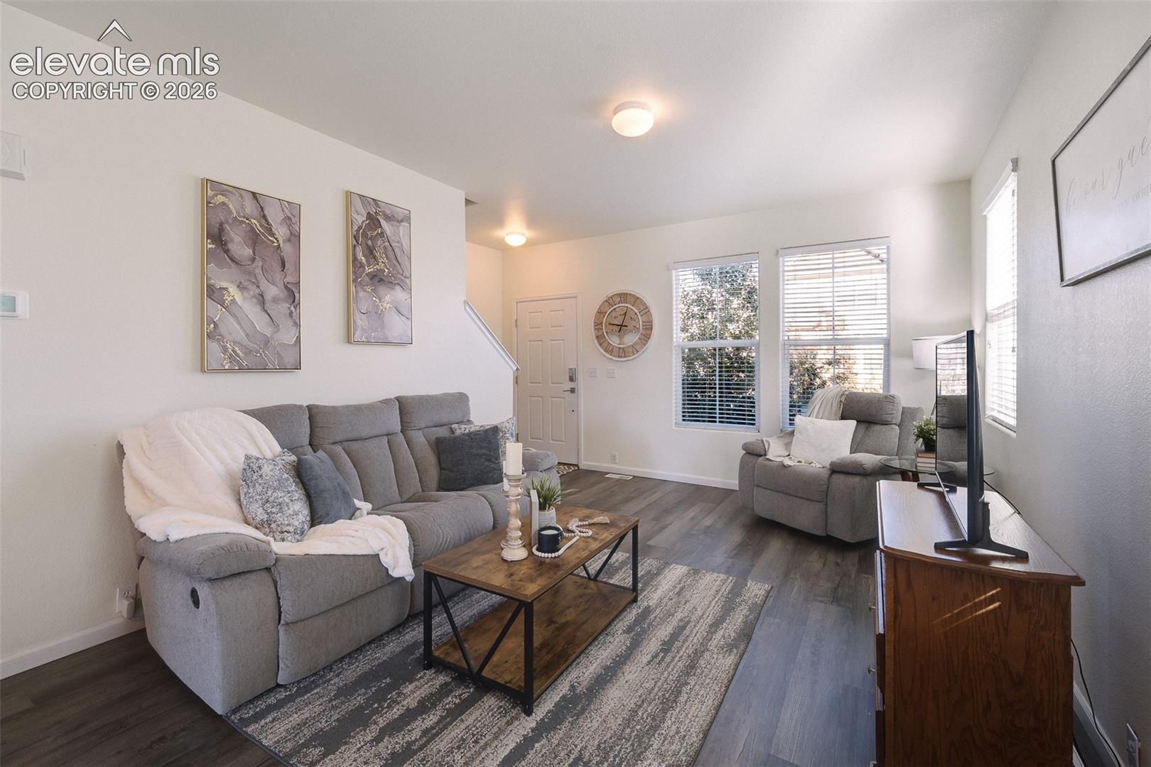 Wood-finish flooring throughout, multiple windows with blinds, recessed lighting, and a white interior door with hardware