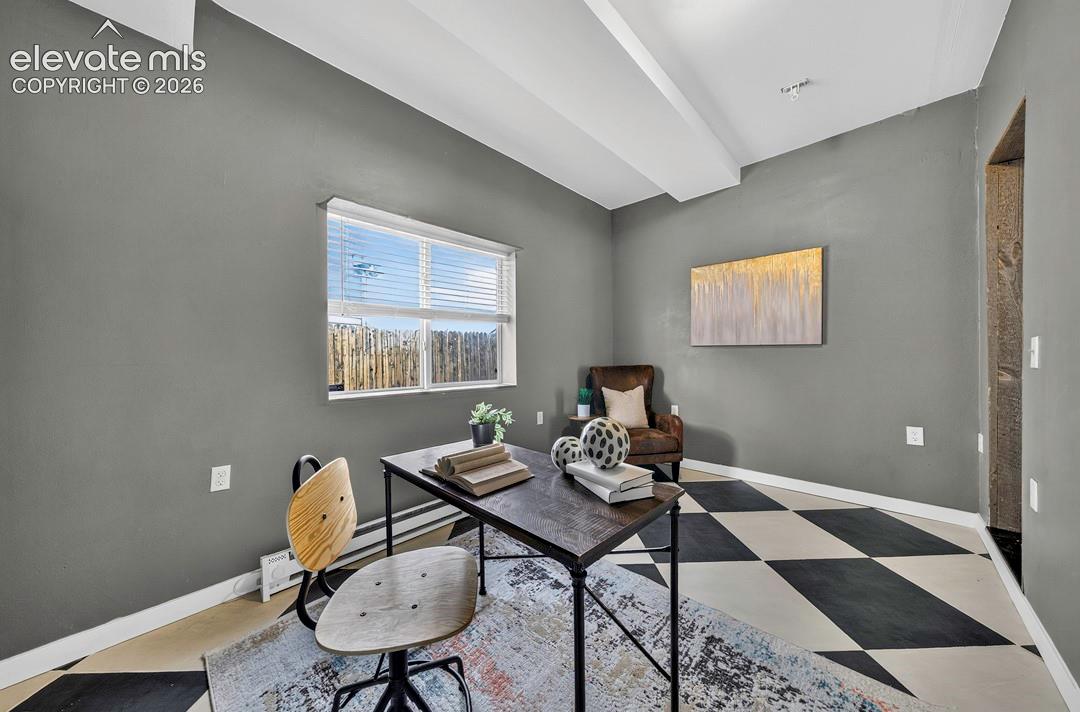 Interior room featuring high ceilings, a single-pane window with integrated blinds, and a bold diamond-patterned floor finish