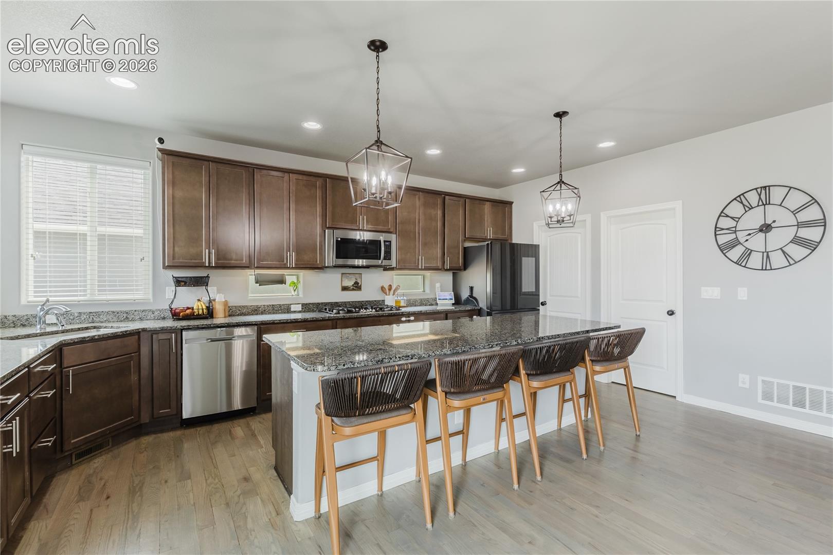 Contemporary kitchen featuring wood-finish flooring and a central island with bar seating