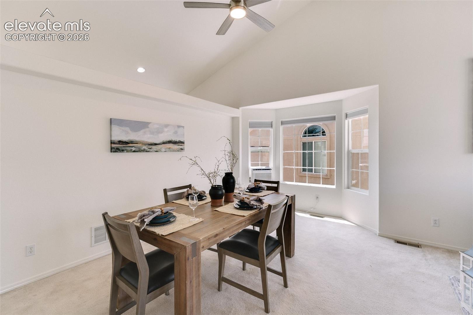 Vaulted ceiling with a ceiling fan, recessed lighting, and a bay window
