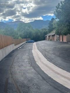 Paved driveway with a concrete retaining wall, wood fencing, and adjacent covered parking structures