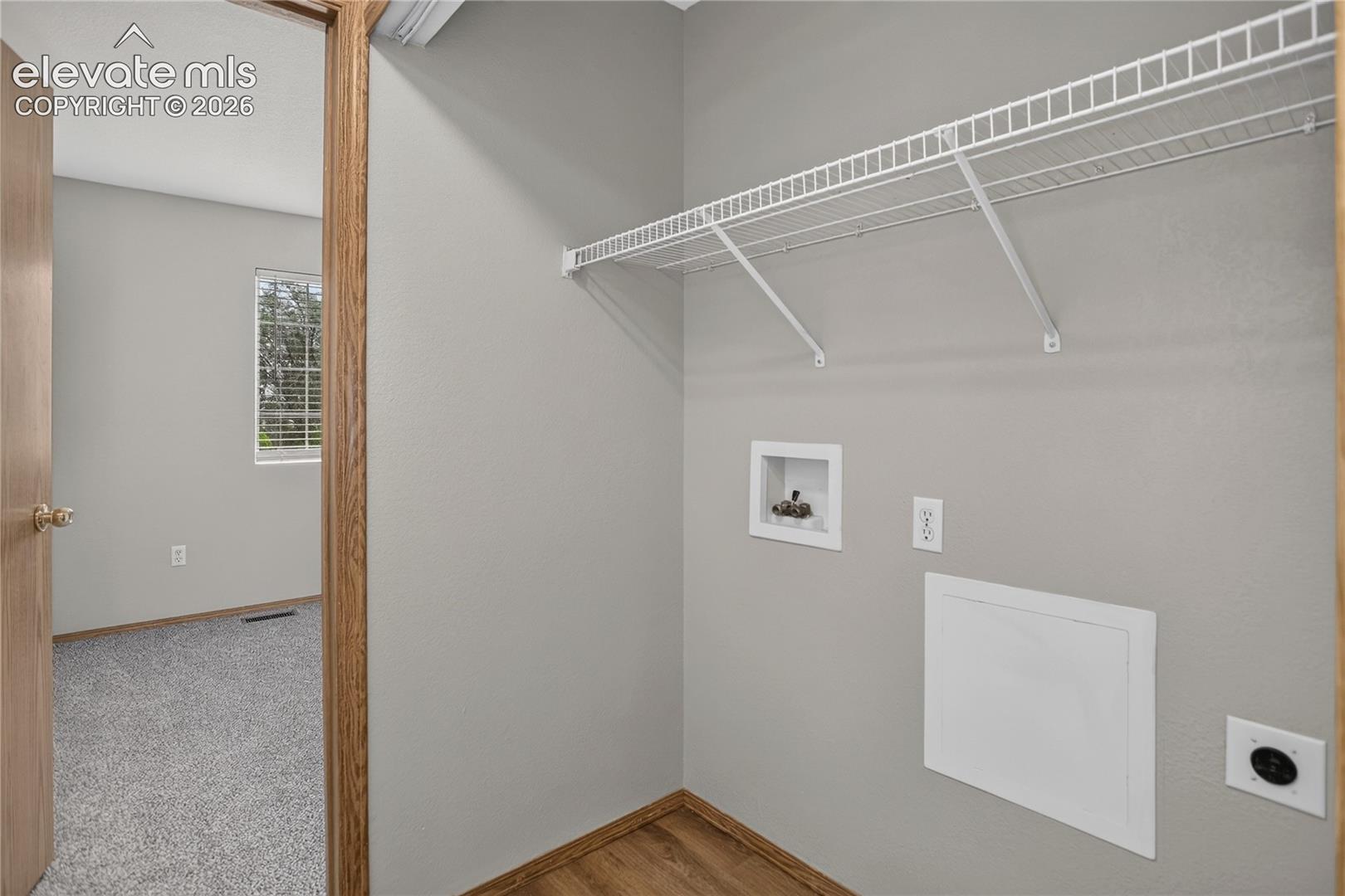 Utility area with wood-finish flooring, wire shelving, and appliance hookups