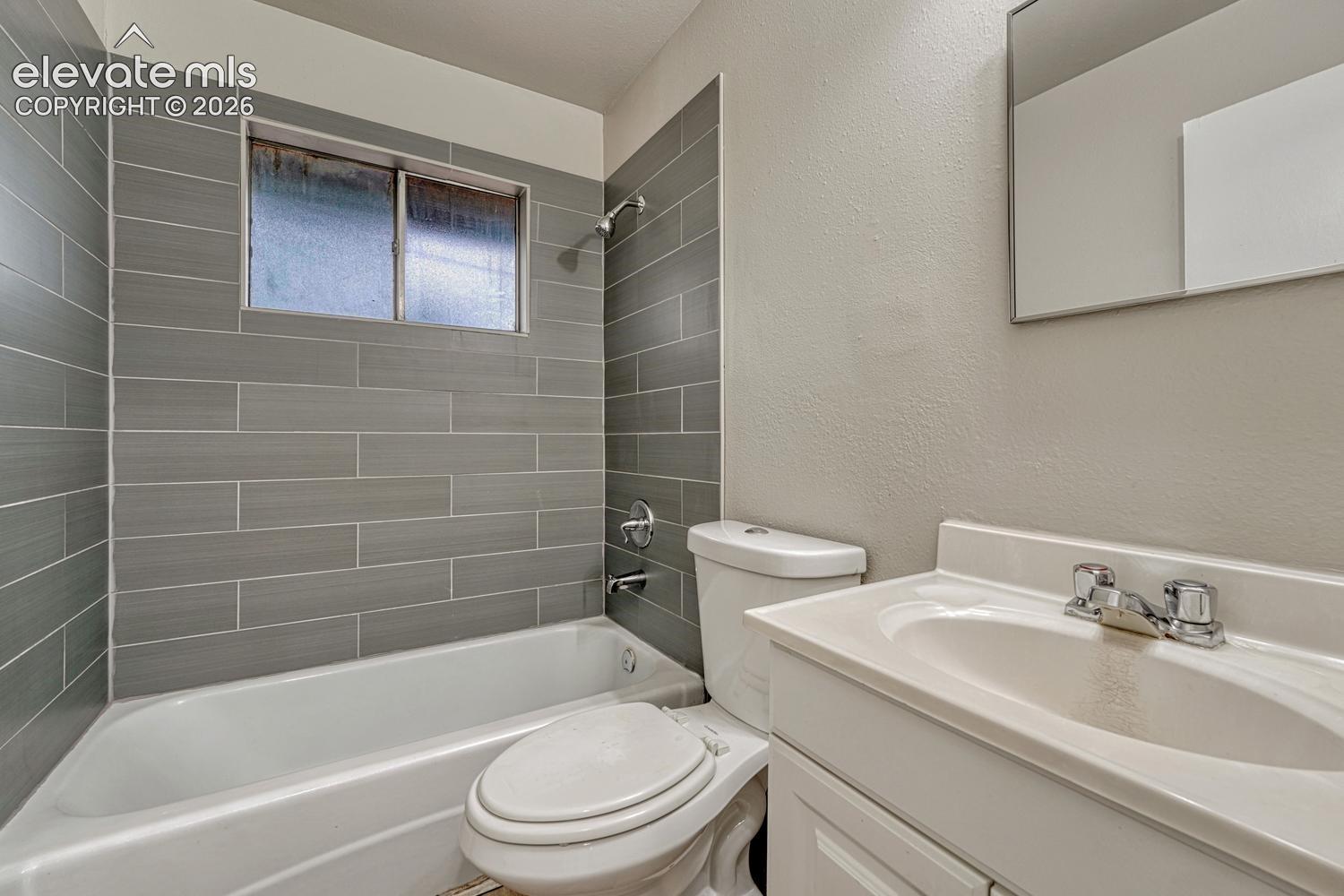 Bathroom with subway-tiled shower surround, integrated bathtub, and a single vanity with a basin sink and chrome fixtures