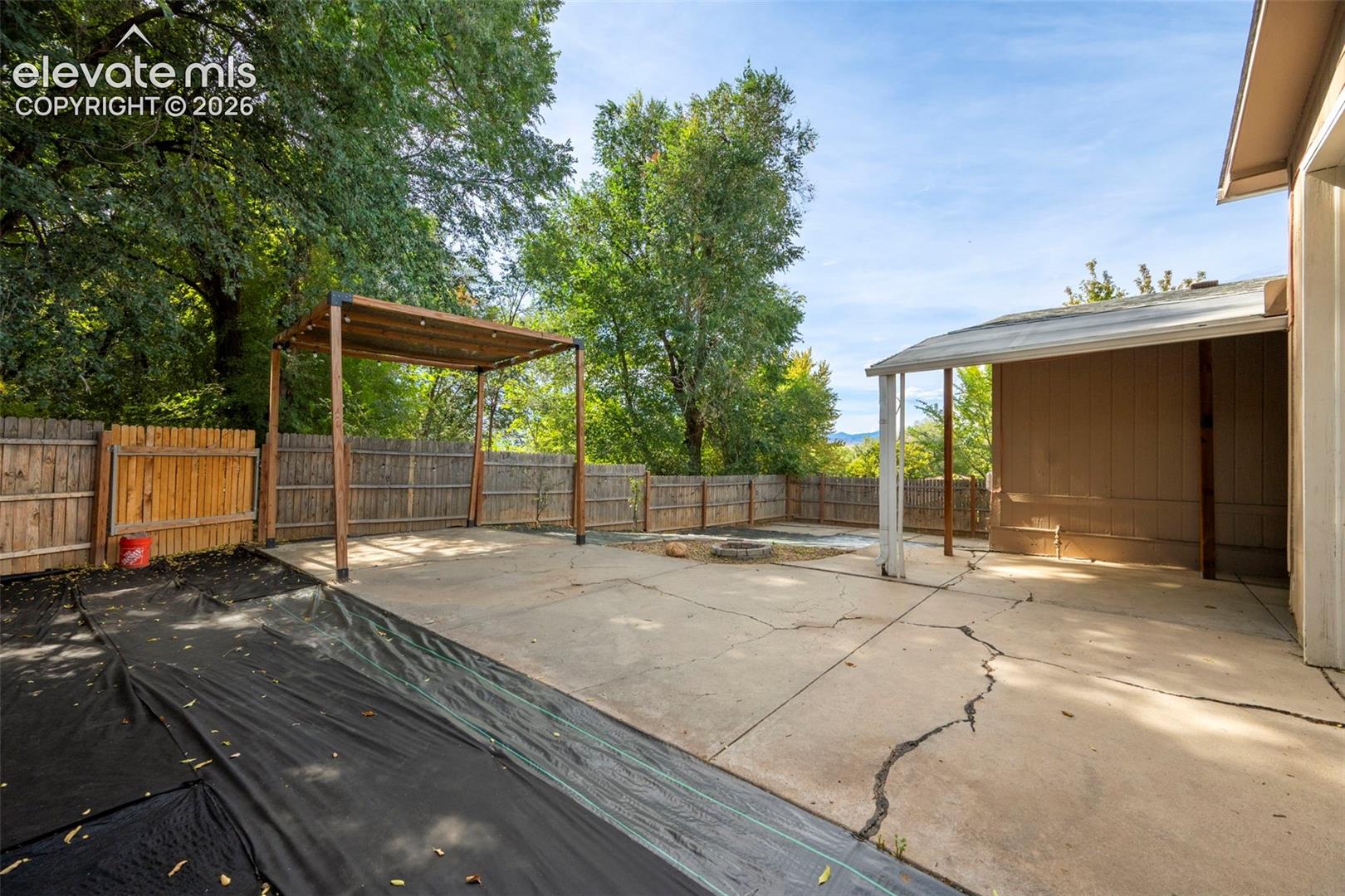 Concrete patio featuring a wooden pergola, covered patio area, and wood privacy fencing