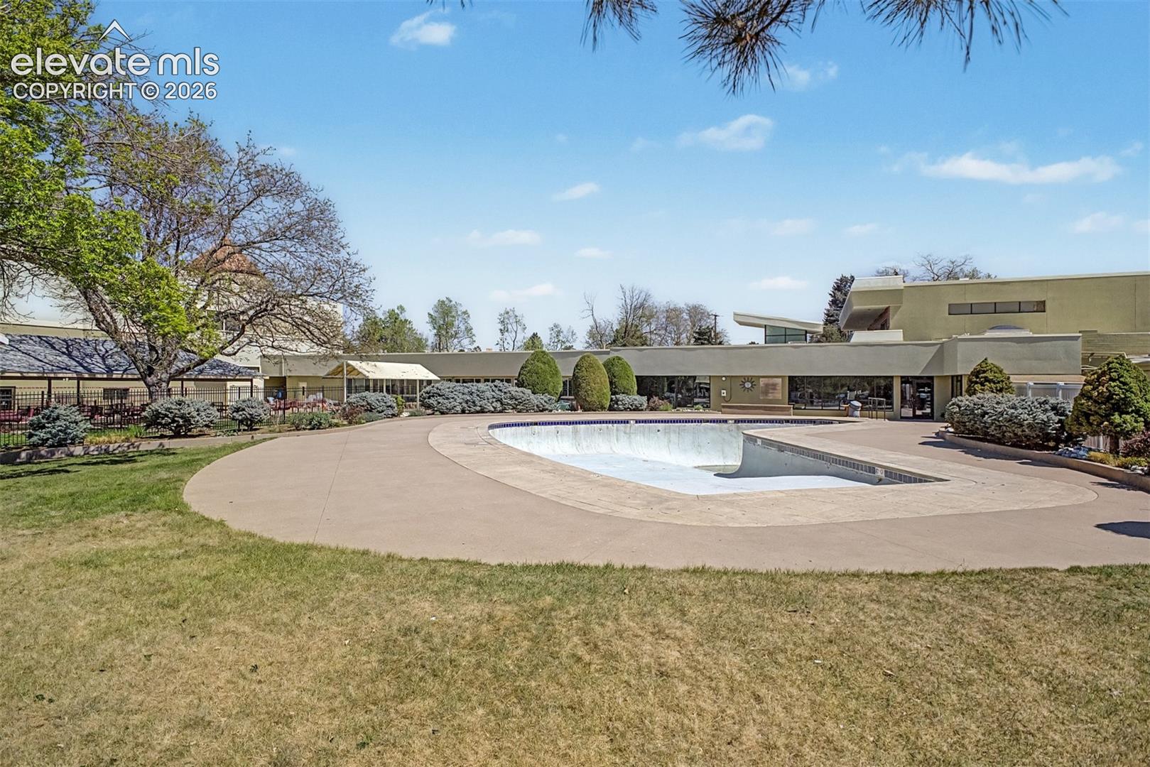 Expansive outdoor space featuring a kidney-shaped pool, concrete patio, and a grass lawn