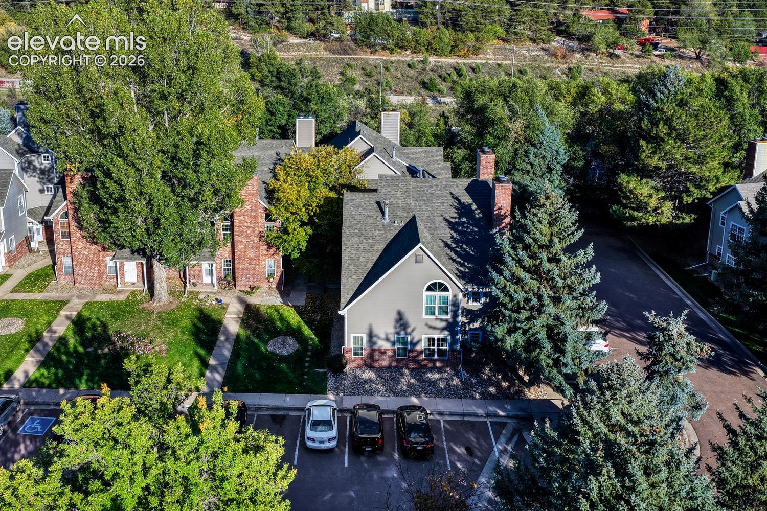  Brick and siding exteriors, gabled roofs, multiple chimneys, mature trees, and a mountainous backdrop
