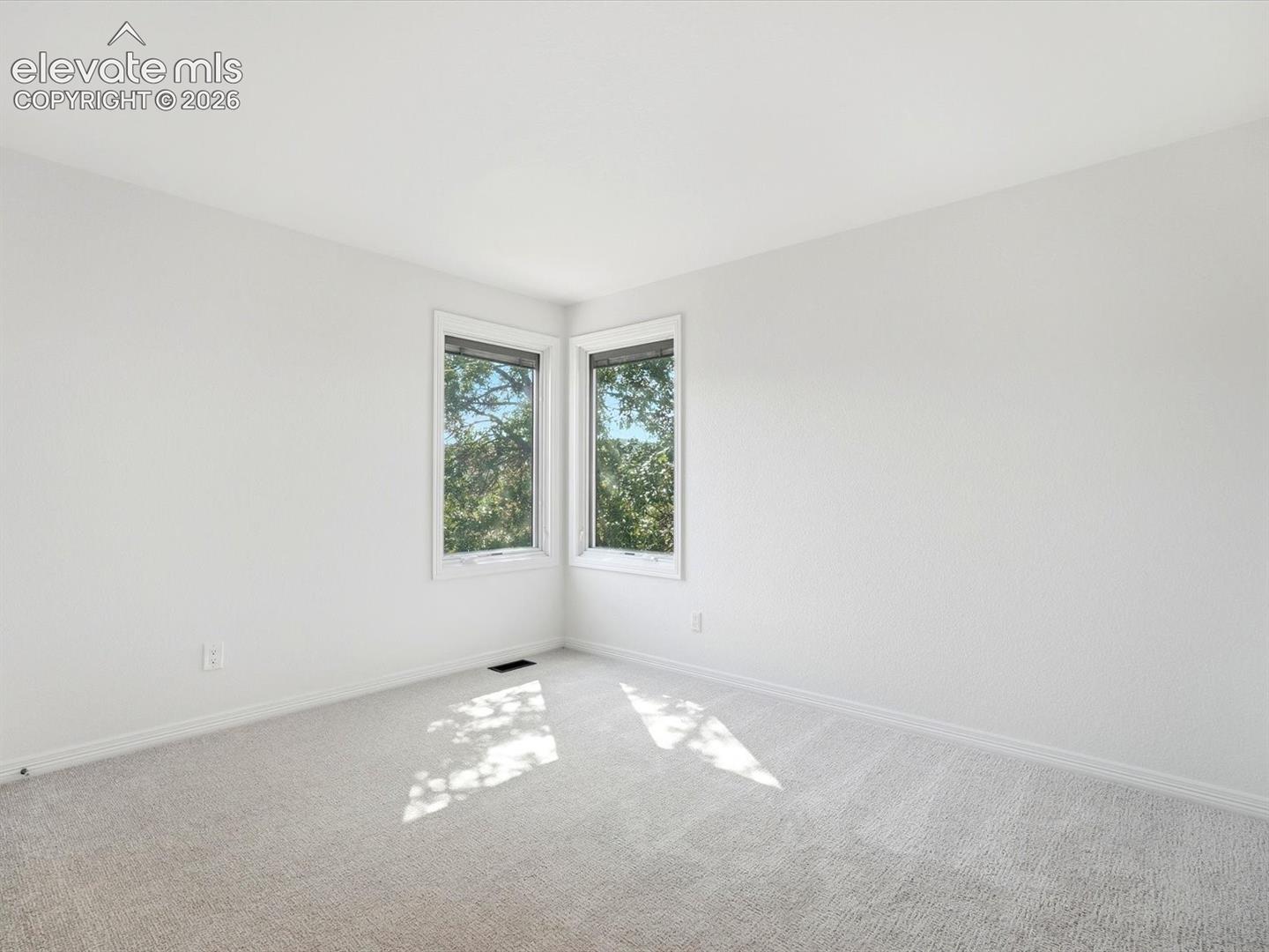 Neutral-toned wall-to-wall carpeting and dual corner windows
