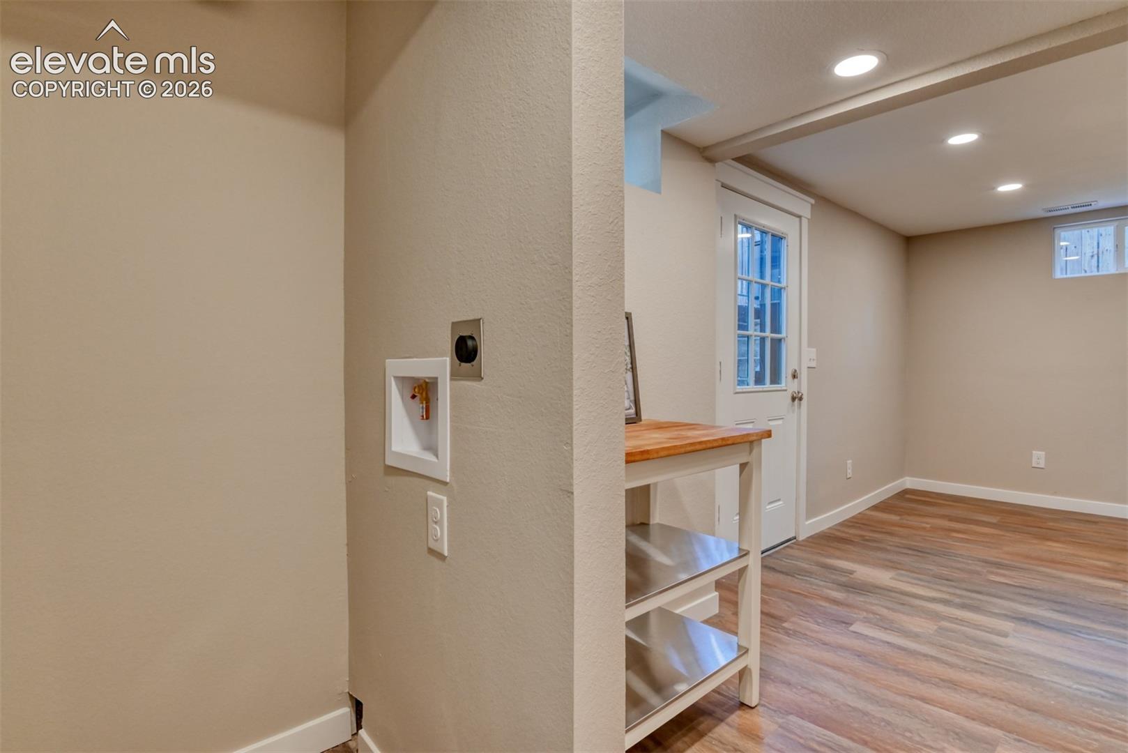 Recessed ceiling lighting, wood-finish flooring, white trim, and a white paneled door with glass inserts