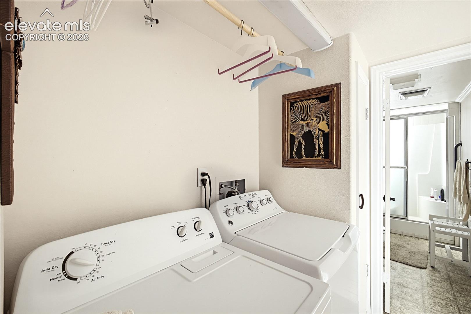 Dedicated utility area featuring a mounted clothes rod, overhead linear lighting, and wall-mounted electrical outlets