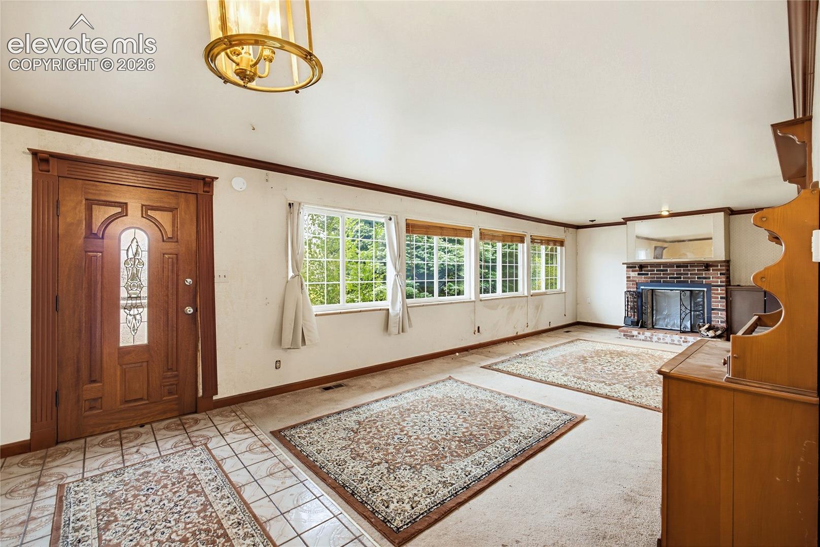 Entryway featuring a decorative wood door with leaded glass, tile flooring, and an overhead brass-finish light fixture