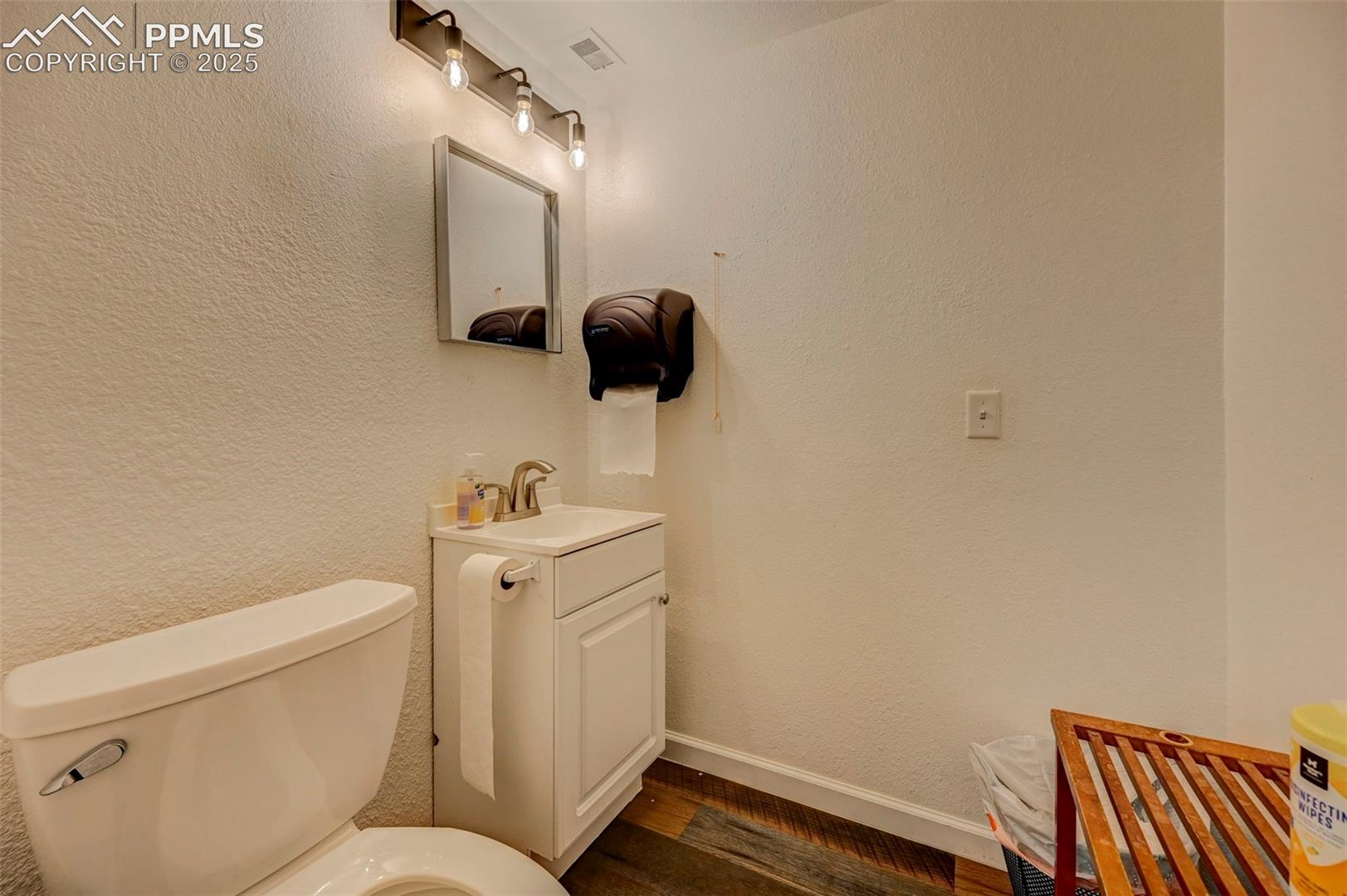 Bathroom with vanity, toilet, wood finished floors, and baseboards