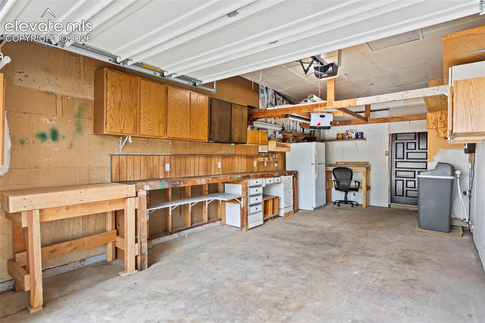 Garage with overhead door, built-in wooden workbench, and overhead cabinetry