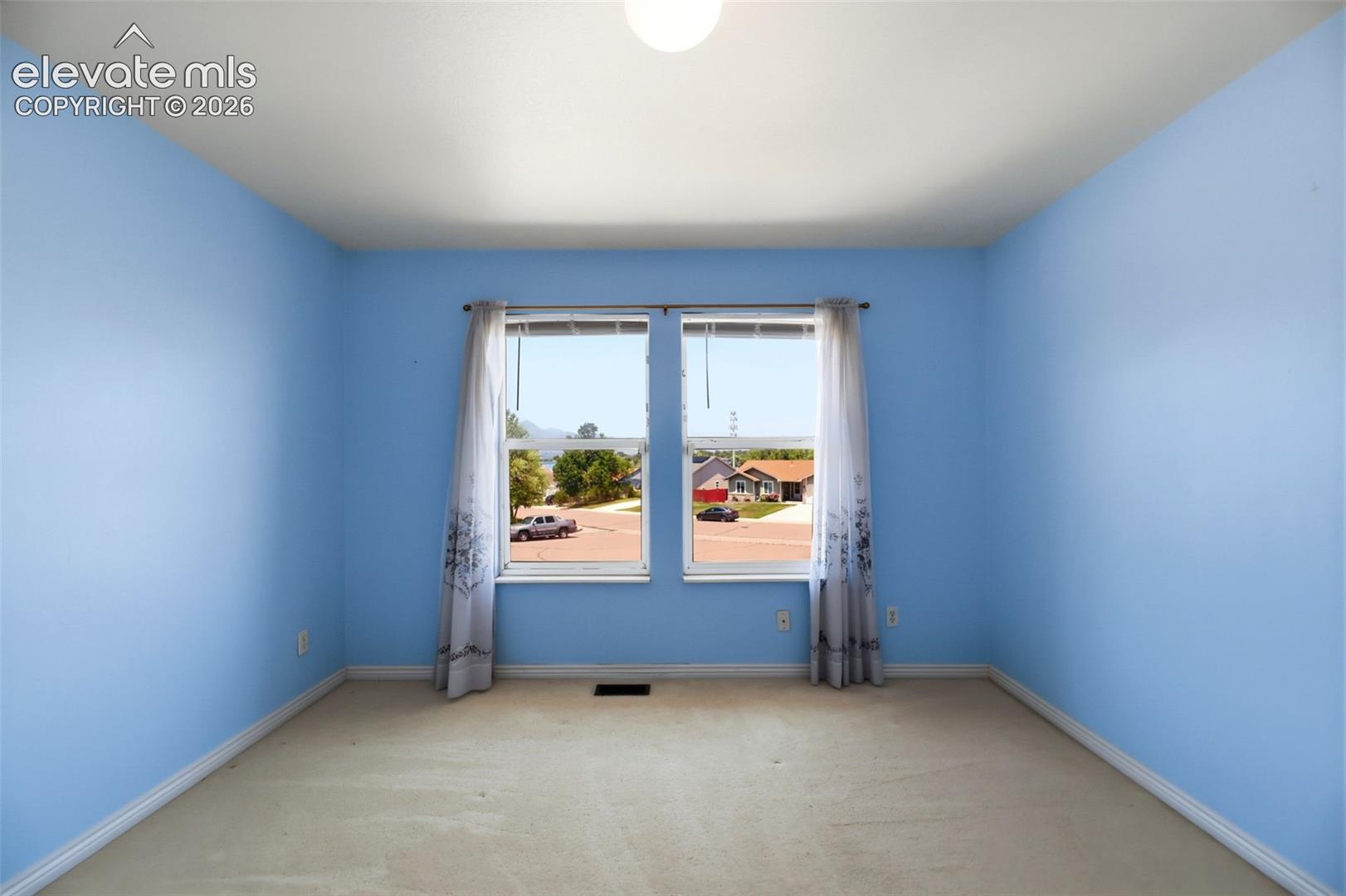 Room featuring two windows with white frames, light blue painted walls, and white baseboards