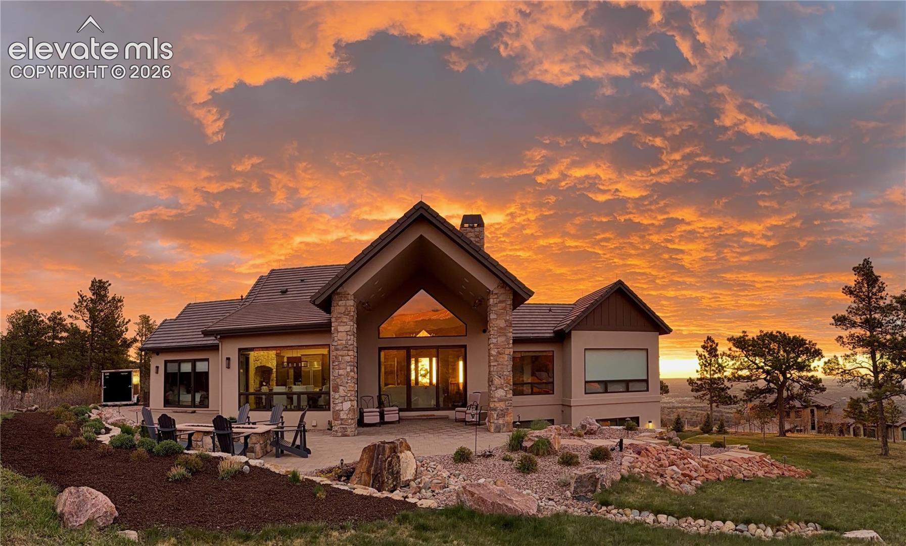 This is what golden hour looks like at 7,645 feet. Rear exterior at sunset, framed by Colorado pines, custom stonework, and a sky that puts on a different show every night.