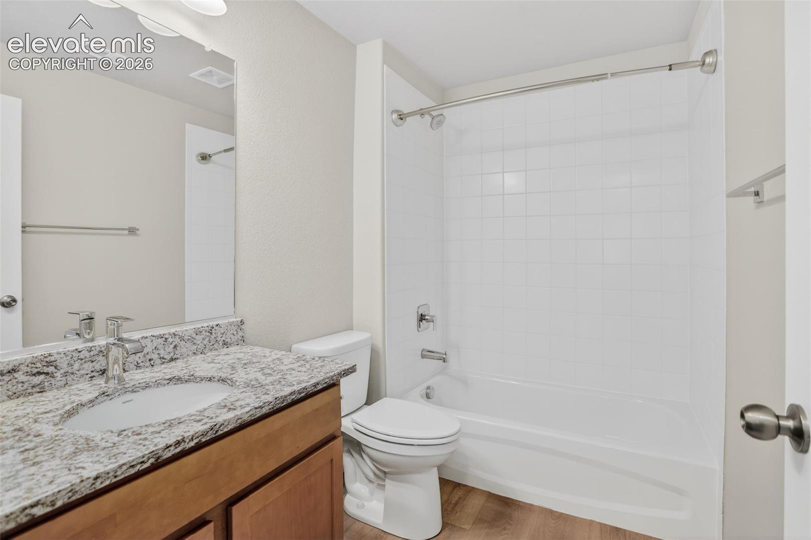 Bathroom featuring a single vanity with a granite-style countertop, undermount sink, and chrome faucet