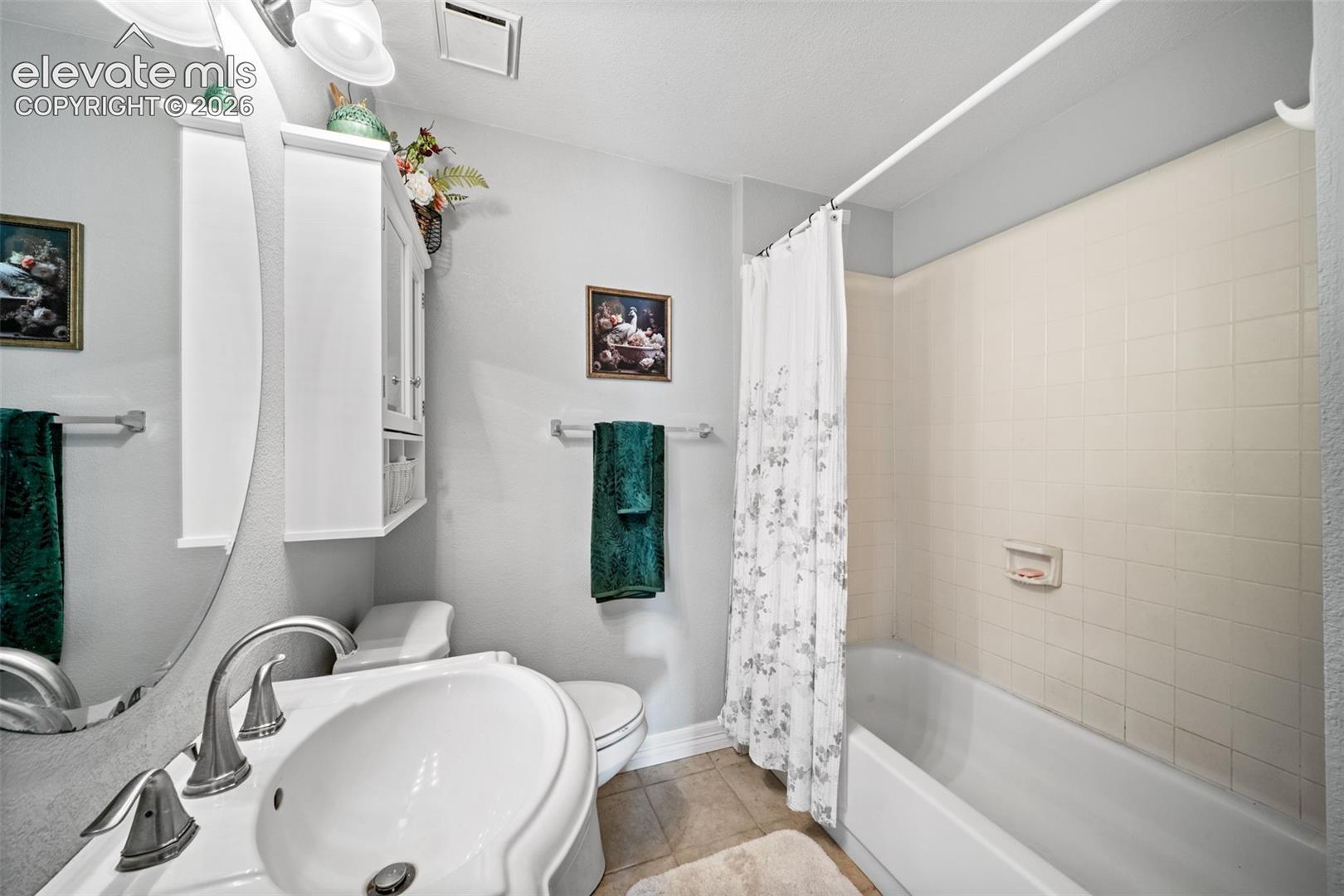 Full bathroom featuring a pedestal sink with brushed nickel faucet, a wall-mounted storage cabinet, and a bathtub with tiled surround