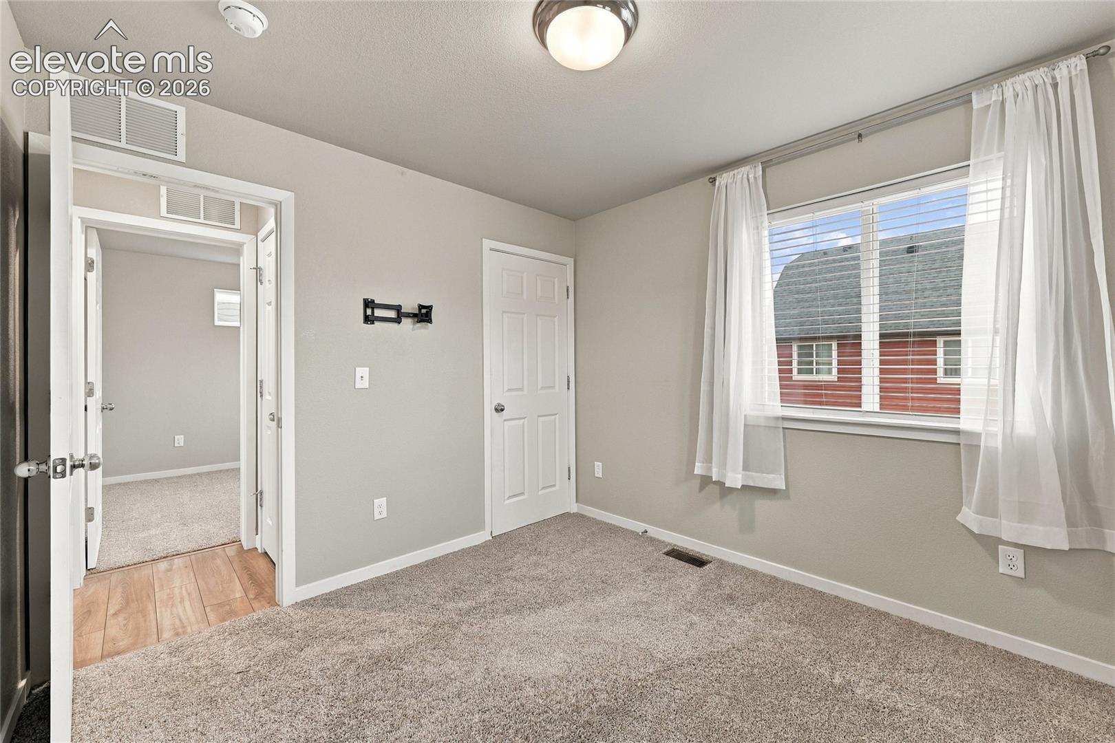 Carpeted room with a window, ceiling-mounted light fixture, and white trim