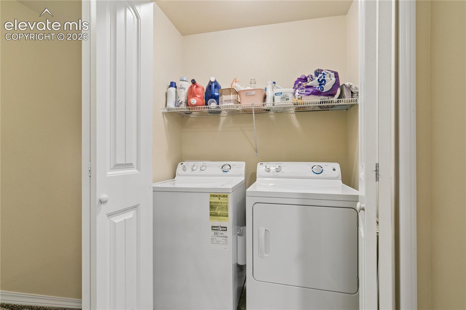 Dedicated laundry area featuring a white top-load washer, a white front-load dryer, and an upper wire shelf for storage