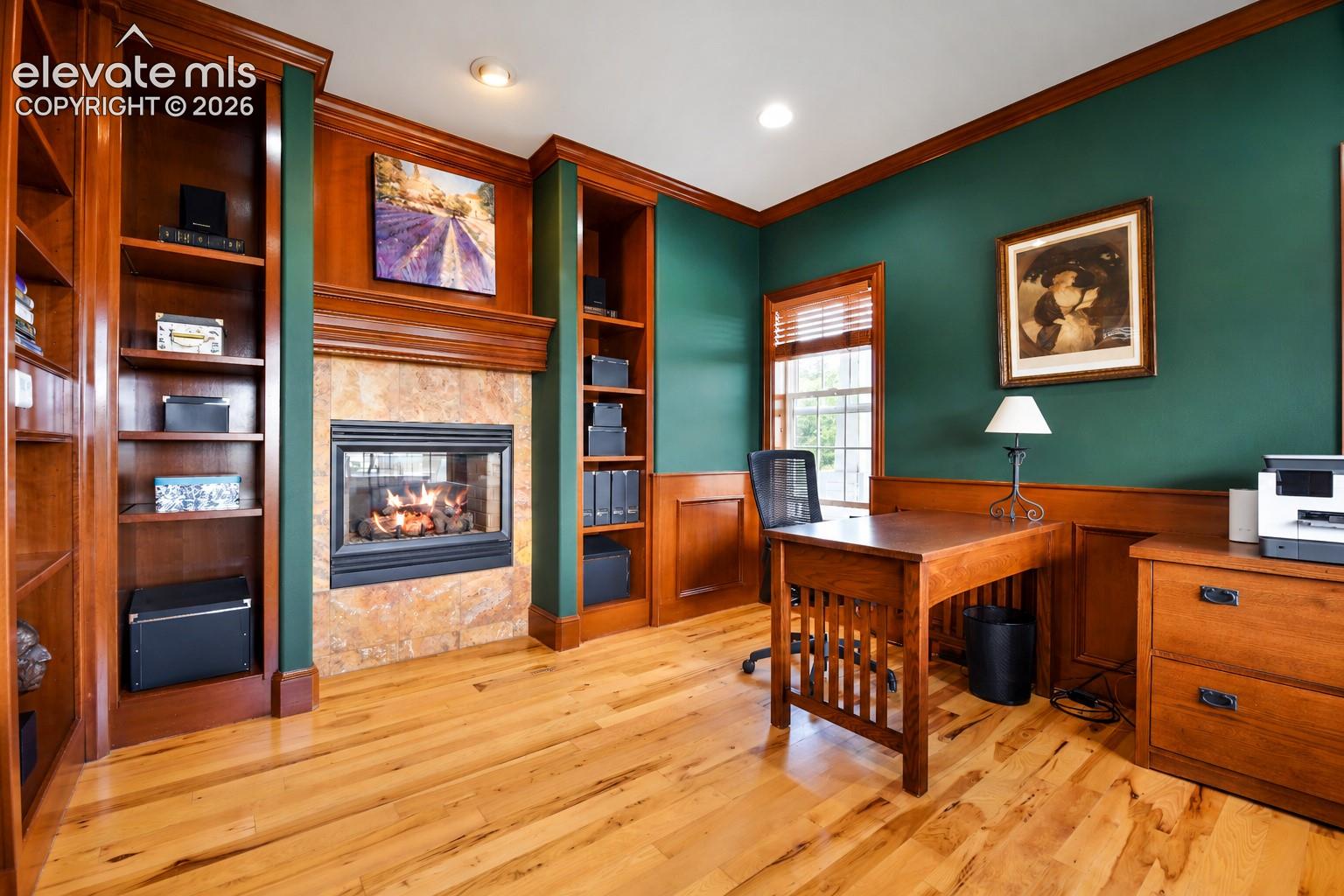Office has crown molding, built-in shelves, raised panel wainscoting and two-sided fireplace...