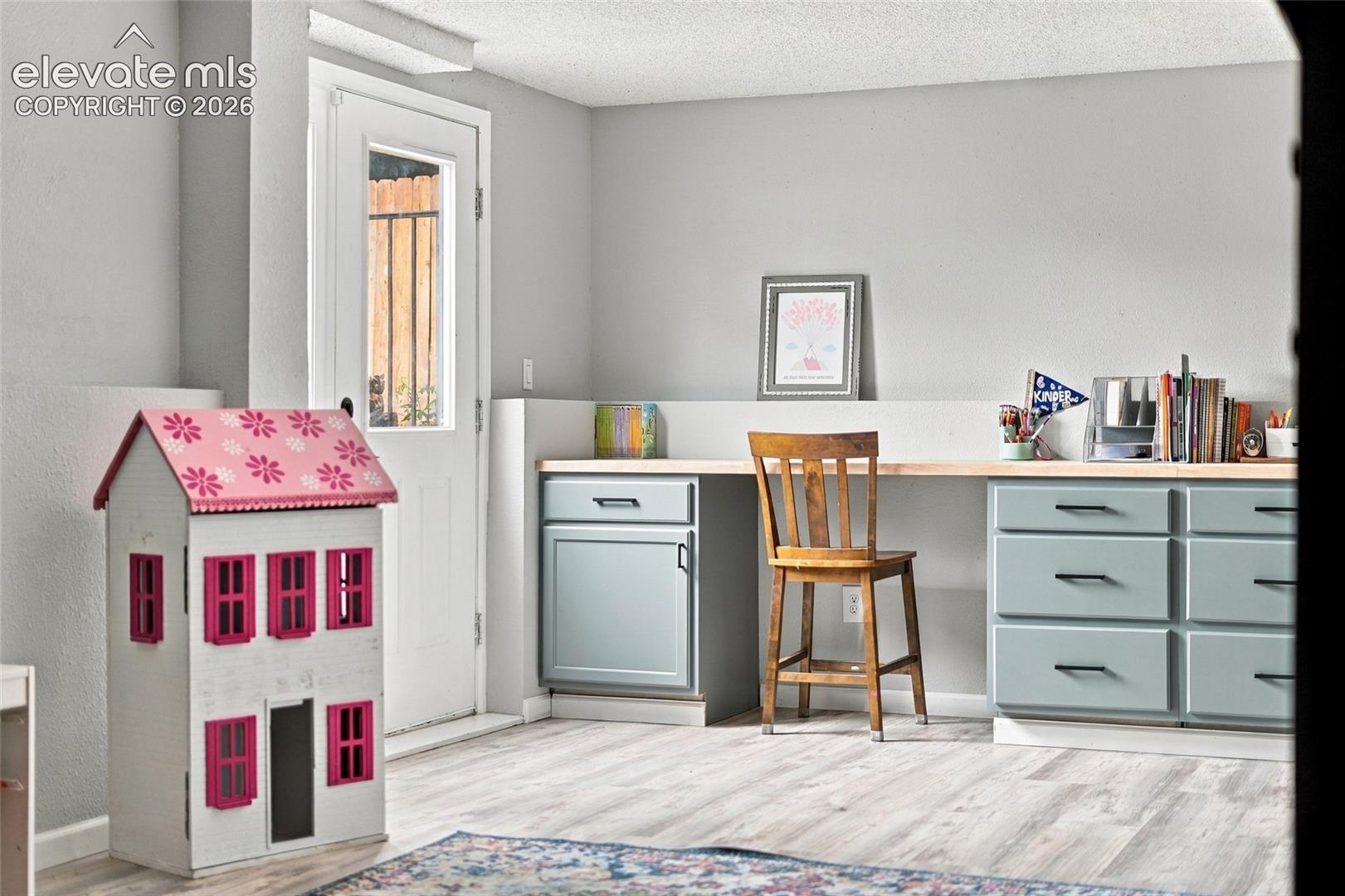 Built-in desk with a wood-finish countertop, light blue cabinetry, and black hardware