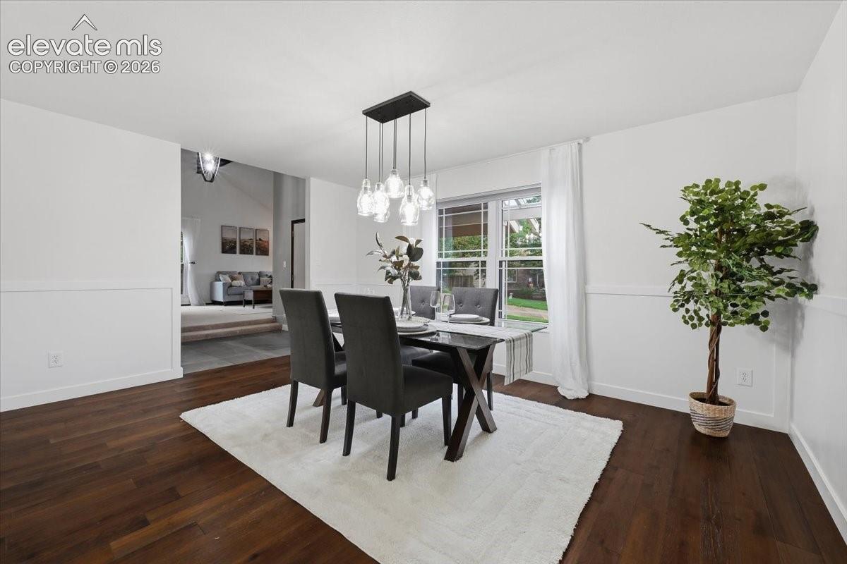 Wood flooring, wainscoting, and a modern rectangular chandelier with clear glass shades