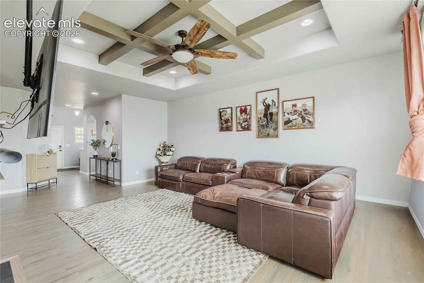 Living area featuring a coffered ceiling with a wood-finish ceiling fan and recessed lighting