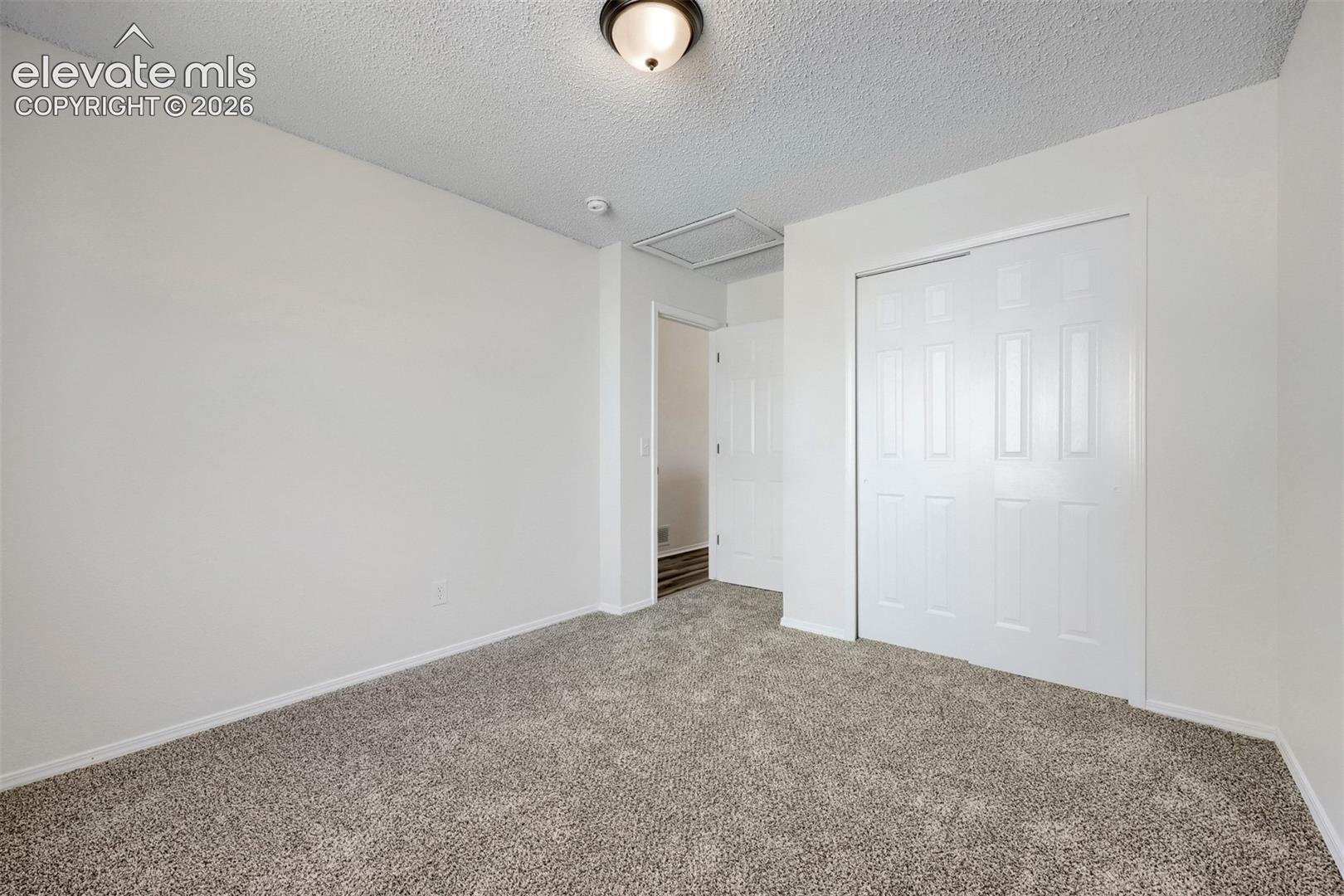 Plush grey carpet, white painted walls, and white bi-fold closet doors