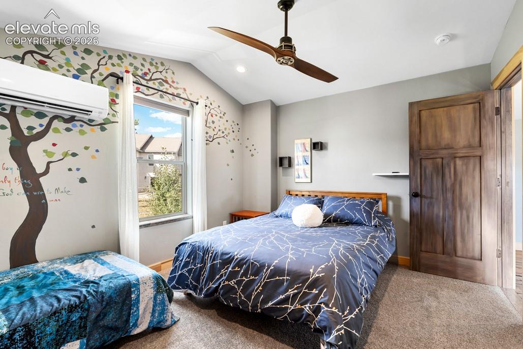 Vaulted ceiling, ceiling fan, wood-finish door, window with natural light, wall-mounted air conditioning unit