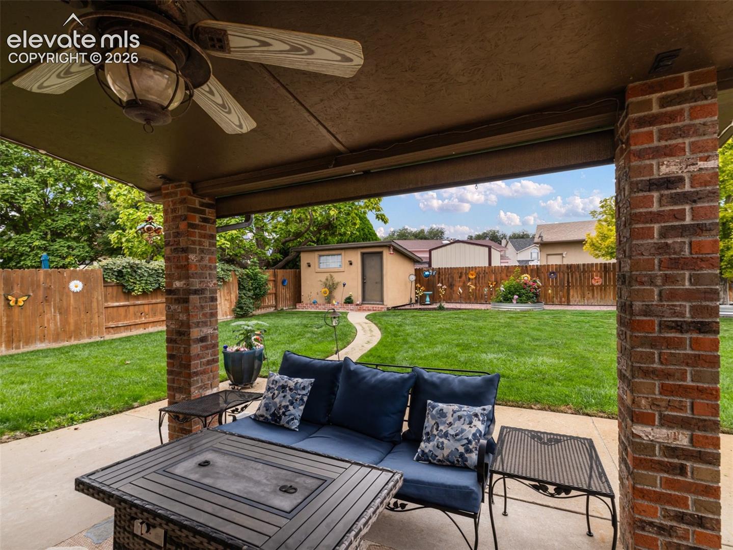 Covered patio with a ceiling fan and brick pillars