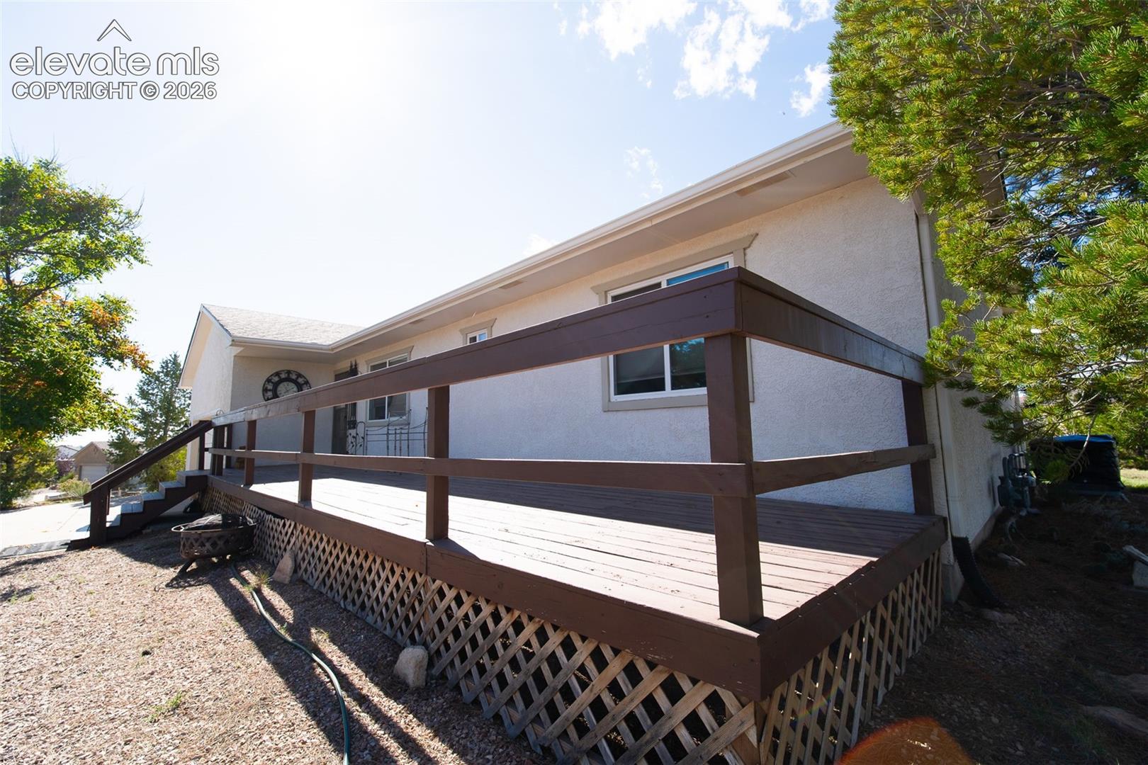 Stucco exterior featuring a raised wood deck with lattice skirting and a perimeter railing