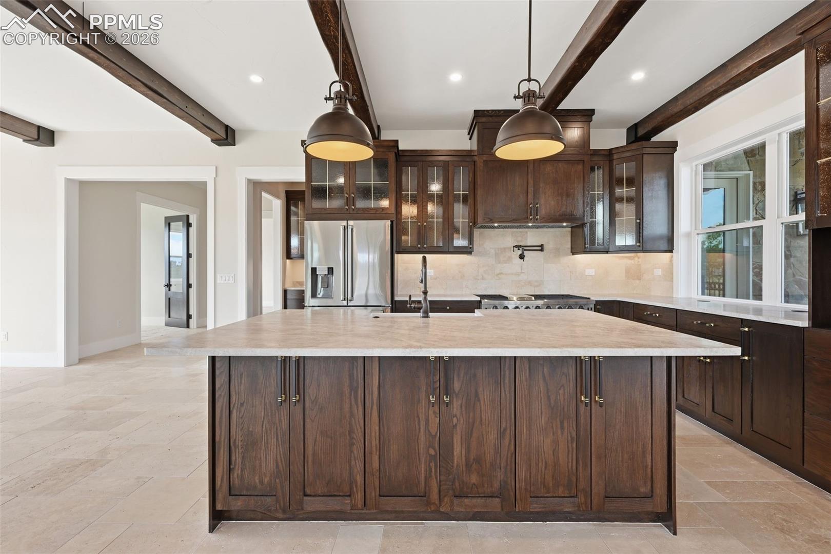 Kitchen featuring dark wood finish cabinets, stainless steel fridge with ice dispenser, decorative backsplash, glass fronted cabinets, and hanging light fixtures
