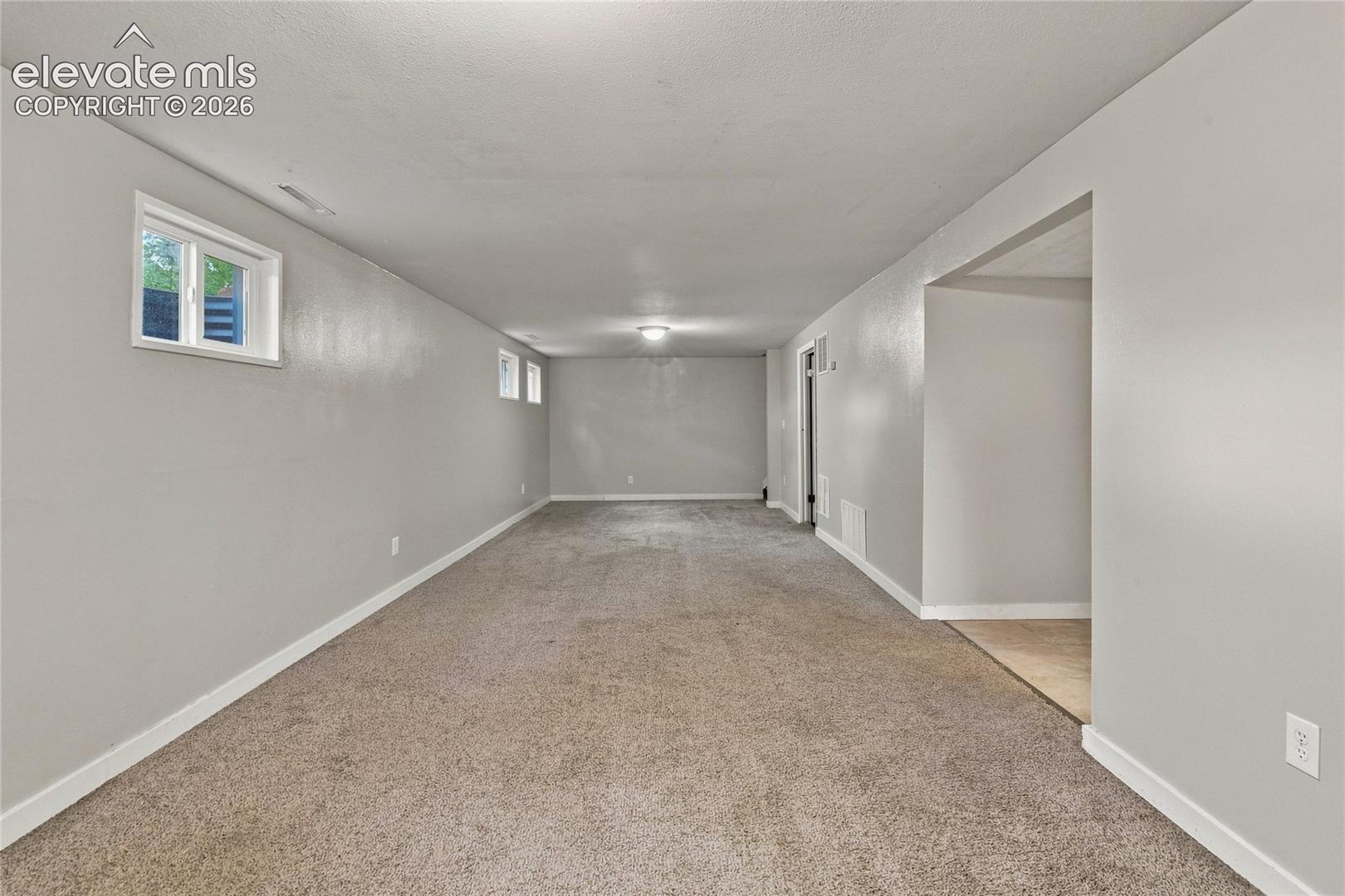 Recessed lighting, light gray wall paint, white trim, light brown carpet, and a framed opening