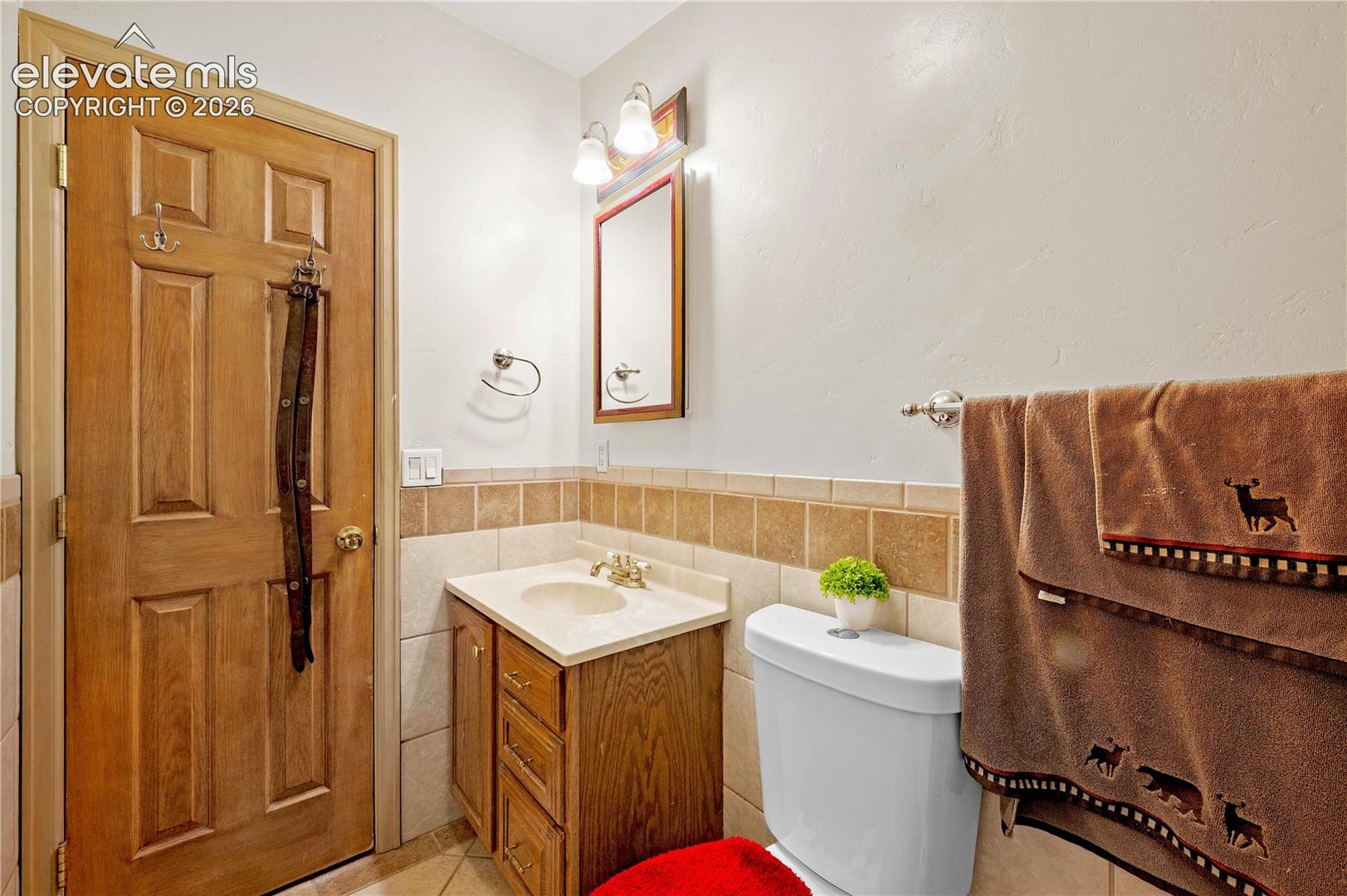 Bathroom featuring vanity, toilet, tile patterned floors, and tile walls