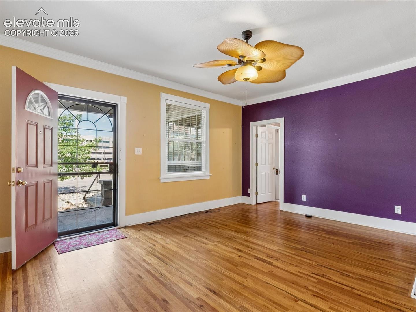 Entry area featuring wood-finish flooring, a decorative ceiling fan, and a paneled entry door with an arched transom window