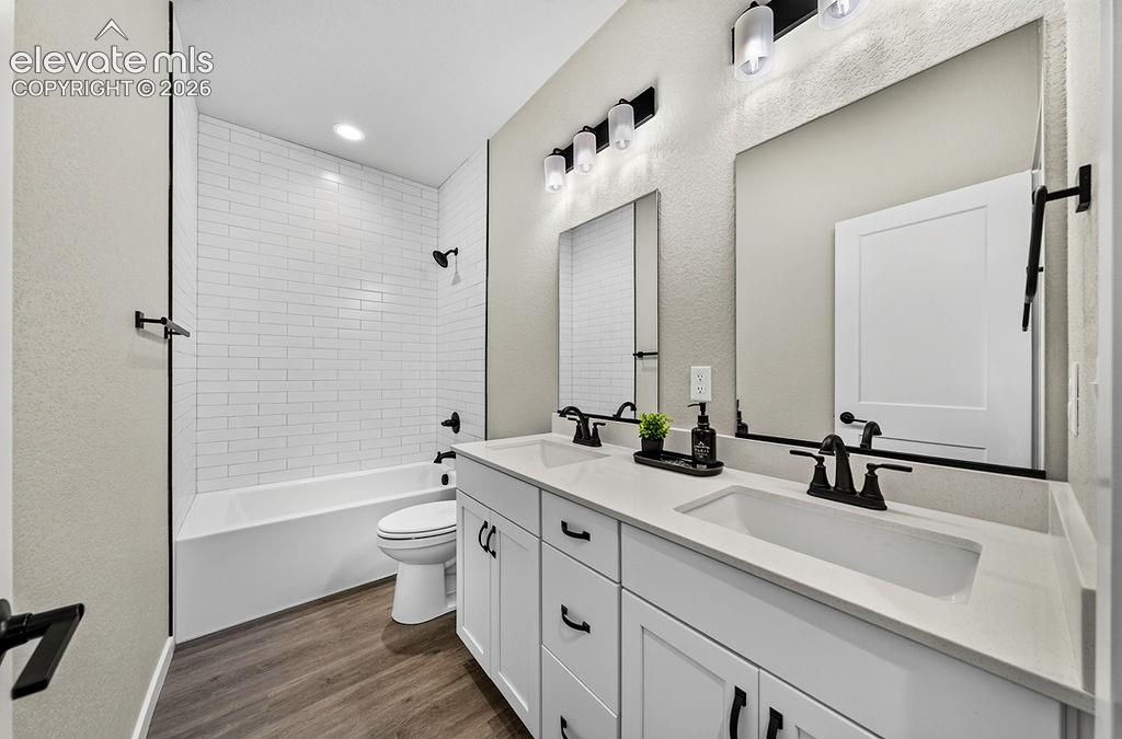 Bathroom featuring a double vanity with white cabinetry and integrated sinks, white countertops, and black hardware