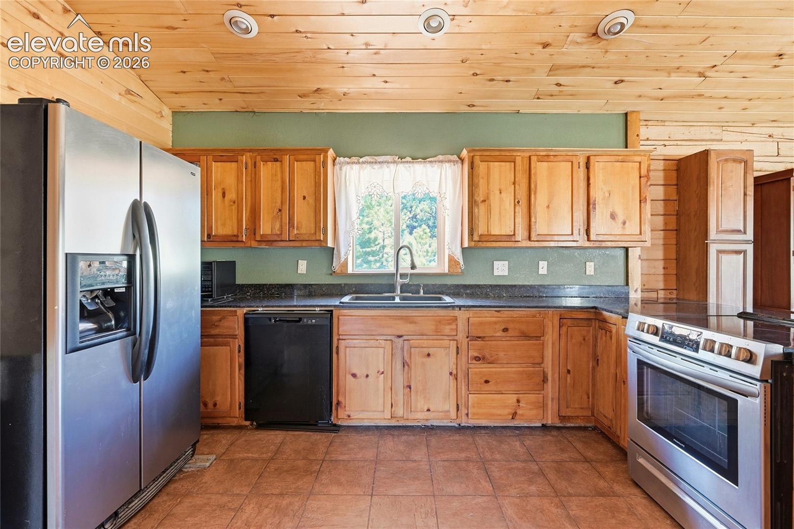 Kitchen featuring wood-finish cabinetry, solid surface countertops, tile flooring, and recessed lighting